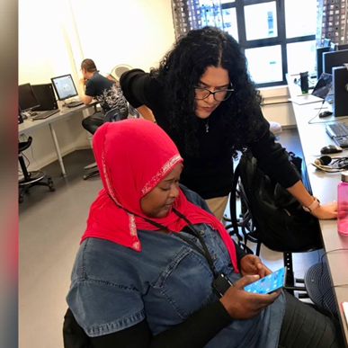 Foto av redaksjonen i arbeid: Mercedes fra Peru og Thiaba fra Senegal jobber med å transkribere et lydopptak. I bakgrunnen lager Peng fra Kina QR-koder til avisen.